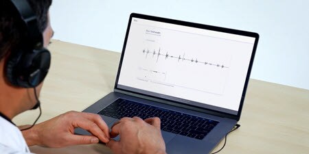 Klinický lékař používá notebook a dívá se na živé video auskultace na notebooku

