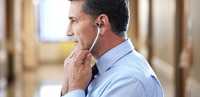 Lékař správně vkládající ušní olivky fonendoskopu Littmann směřující dopředu.
