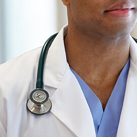 Fonendoskop Littmann se správně nosí vně límce bílého lékařského pláště, který zabraňuje, aby se hadičky dotýkaly krku lékaře.