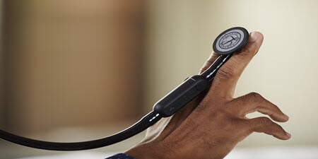 Detailní záběr digitální fonendoskopu Littman CORE, který je umístěn na prstech.
